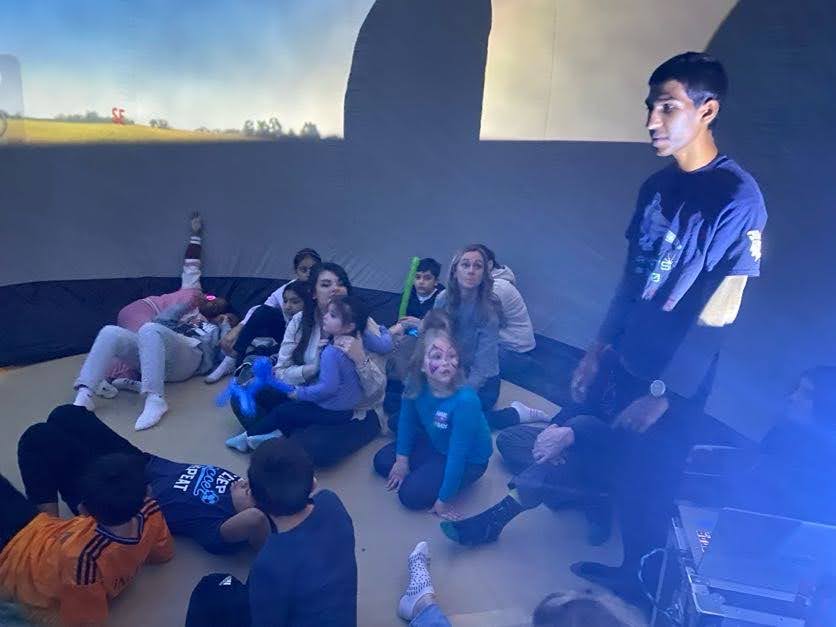 Nash showing the stars to younger students in the planetarium